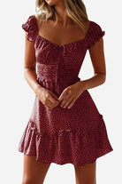Woman wearing a red sweetheart collar printed ruffled maxi dress with off-shoulder sleeves and polka dot pattern