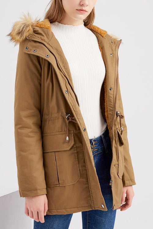 Women wearing a large hooded velvet coat in brown with fur trim and multiple pockets