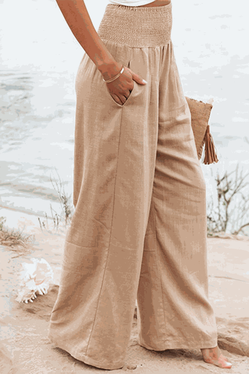 Beige high-waist cotton linen palazzo pants with wide legs and pockets on beach background