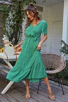 Woman wearing green charming floral boho maxi dress with wrap V-neck and belted ruffle hem outdoors