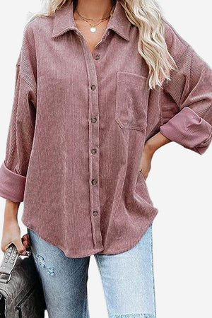 Woman wearing a sleek suede oversized button-down shirt in dusty rose with rolled sleeves and light blue jeans