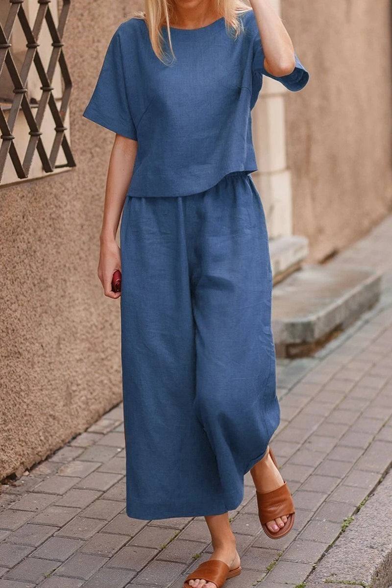 Woman wearing blue loose fit co-ord set with wide-leg pants and short-sleeve top walking on street