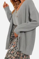 Relaxed fit oversized gray knitwear cardigan with buttons worn over floral dress