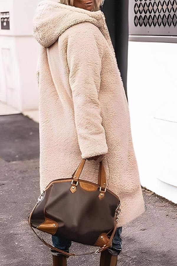 Woman wearing beige Sherpa-lined hooded teddy coat carrying brown handbag outdoors