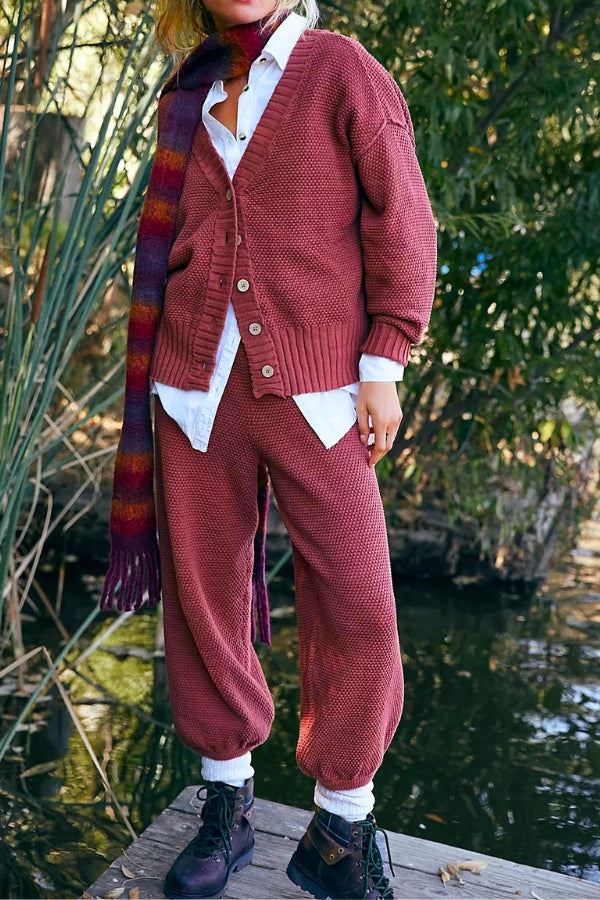 Woman wearing a relaxed two-piece knitwear co-ord set in rust color with buttoned cardigan and jogger pants outdoors