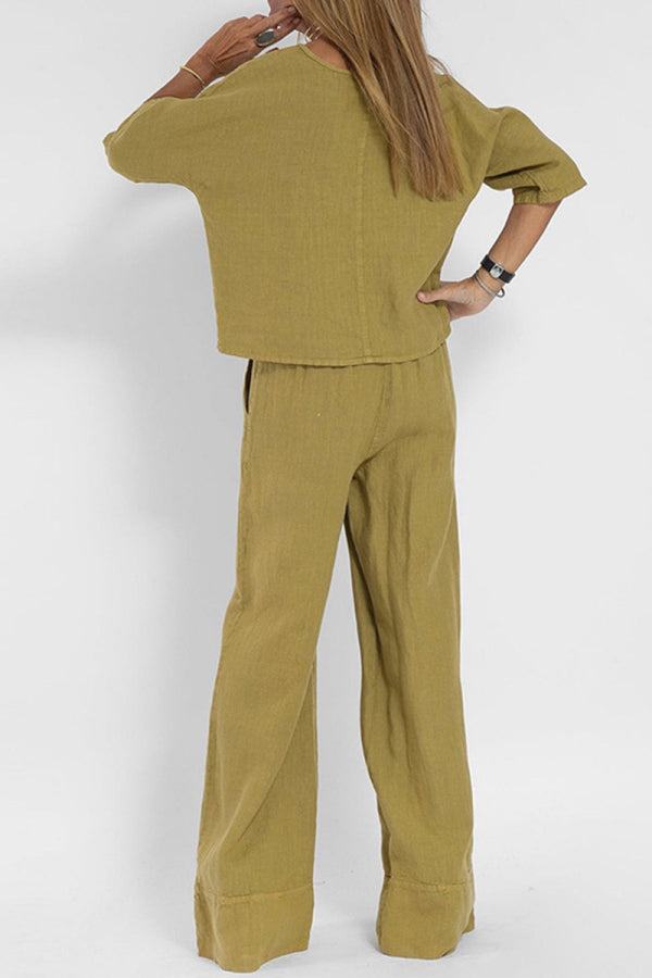 Back view of woman wearing mustard yellow short-sleeved pullover and wide trouser matching set with loose fit and cuffed hems