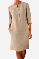 Khaki cotton dress with half-button front, rolled ¾ sleeves, and practical pockets.