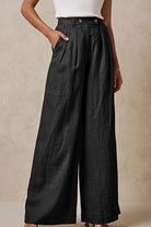 Black wide leg high waist trousers with elastic waistband and pockets worn with a white top