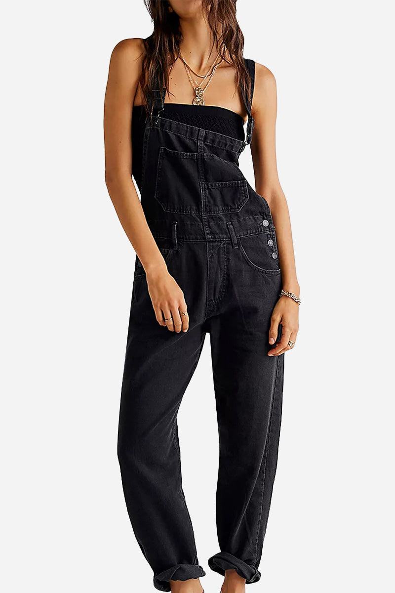 Woman wearing black denim-look tapered-leg adjustable bib overalls with rolled cuffs and black top