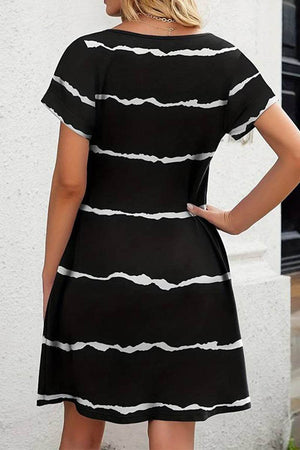 Back view of a black short-sleeved pleated dress with white horizontal stripes and a modest knee-length cut