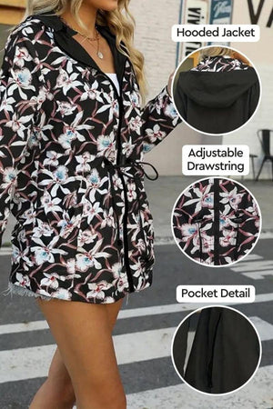 Women's reversible floral raincoat with hood, adjustable drawstring waist, and pockets, featuring black solid and floral print sides.