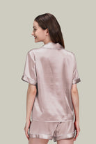 Woman wearing luxurious light pink Mulberry silk buttoned short set nightwear from the back