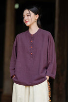 Woman wearing a loose-fit purple ramie linen and cotton blouse with long sleeves and button details