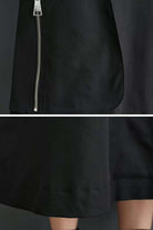 Close-up of black ZipLine Oversized Long Coat showing zipper detail and textured fabric hem.