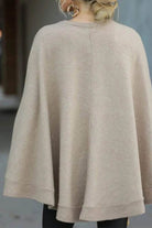 Back view of beige elegant poncho pullover made from soft, lightweight fabric with relaxed fit and ribbed edges