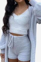 Woman wearing cozy white Cloud Soft 4-Piece lounge set with cardigan, crop top, and shorts made of plush fabric