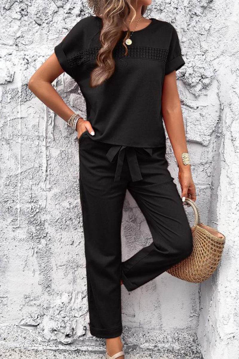 Woman wearing black cotton Total Comfort Two-Piece Set with short sleeves and drawstring pants against textured wall