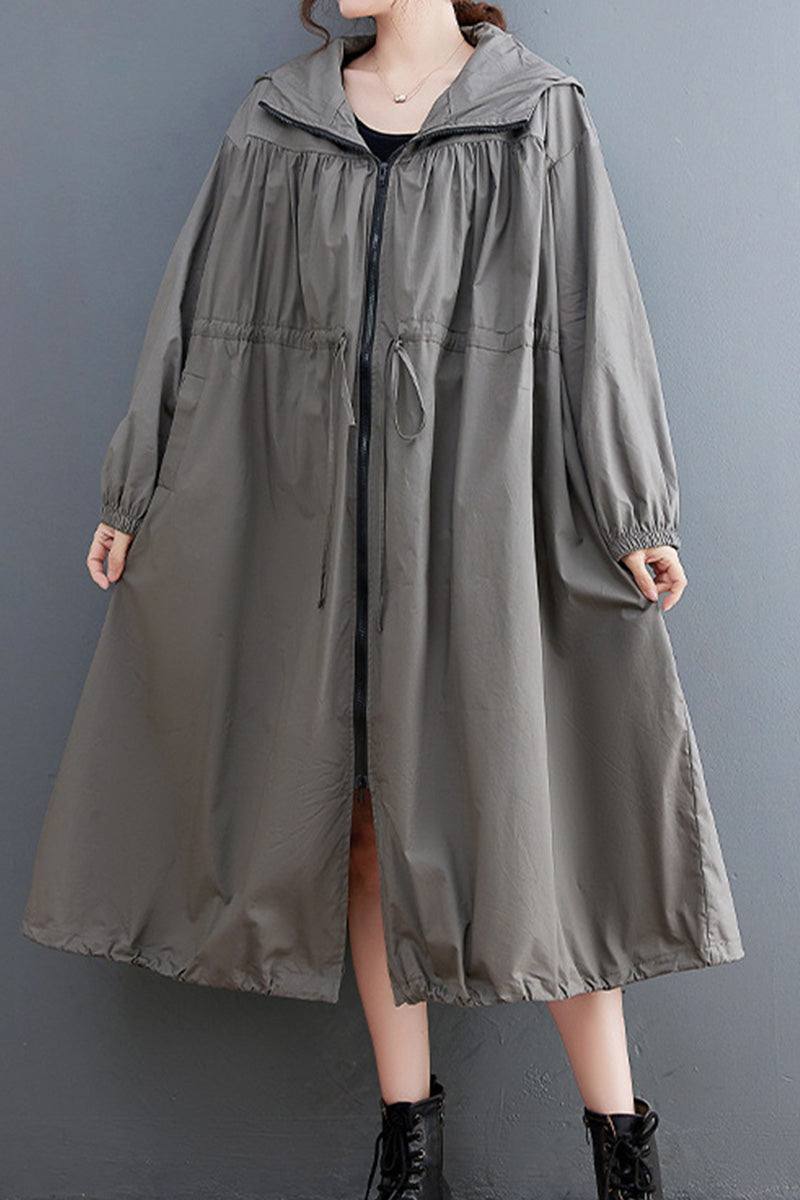 Oversized all-weather water-resistant windbreaker in neutral color with drawstring waist and elastic cuffs, styled with ankle boots