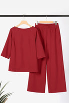 Elegant burgundy textured two-piece set with loose fit top and wide-leg pants on hangers