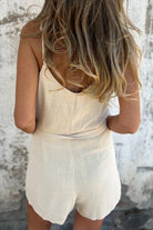 Back view of woman wearing breathable 100% pure linen natural comfort sleeveless jumpsuit with adjustable waist tie.