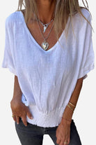 White pure linen short-sleeve blouse with V-neck and relaxed fit on woman