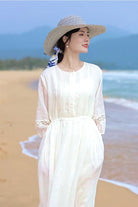 woman wearing white 100 linen coastal shift dress and straw hat on beach