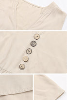 Close-up of beige Bohemian tiered midi dress with V-neck and button detail on lightweight viscose fabric.