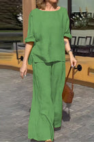 Woman wearing green 100% cotton two-piece set with round neck top and wide-leg pants outdoors.