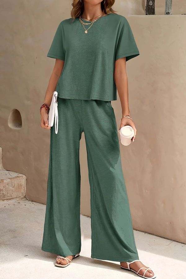 Woman wearing green Riviera Relaxed Two Piece Set with wide-leg pants and short-sleeve top, styled for casual comfort and travel.