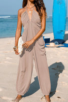 Women's Sunshine On Sand halter-neck wide-leg jumpsuit on beach with elastic ankle cuffs and side pockets.