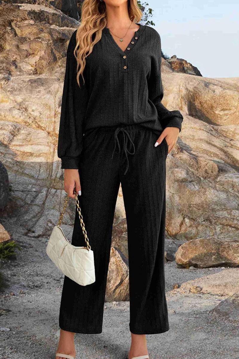 Woman wearing black Desert Bloom Ribbed Comfort Set with V-neck and button details, styled with white handbag and outdoors rocky background