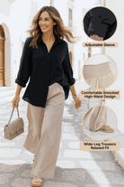 Woman wearing Oversized Linen Leaved-IN Set with black oversized linen-blend shirt and beige wide-leg palazzo pants walking outdoors