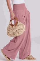 Woman wearing oversized linen leaved-in set with flowy pink palazzo pants and woven handbag