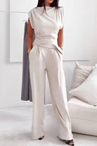 Woman wearing Manhattan Lines Draped two-piece set with asymmetrical draped sleeveless top and wide-leg palazzo pants in light beige