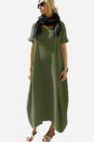 Woman wearing a green Breeze Cocoon Dress with rolled sleeves and a black scarf.