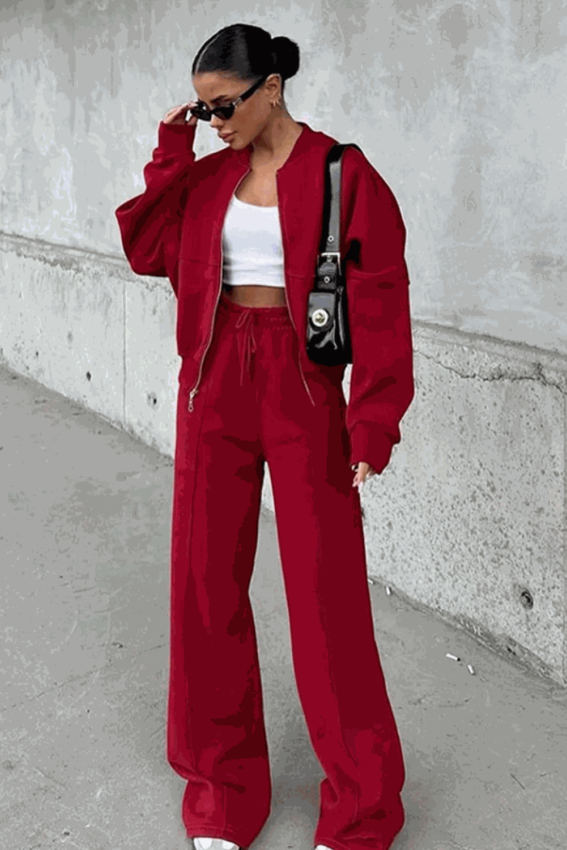 Woman wearing The Voyager Zip Set in red, featuring a relaxed zip-front sweatshirt and wide-leg joggers with pockets.