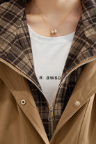 Close-up of City Explorer Plaid Windbreaker with beige wind-resistant shell and soft plaid lining on a white t-shirt background
