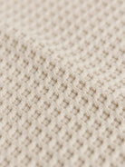 Close-up of soft breathable beige cotton waffle knit fabric texture