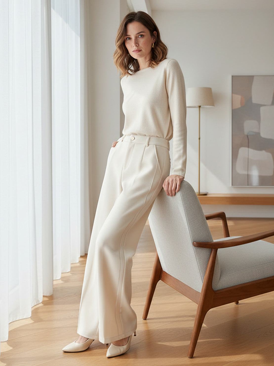 Woman wearing cream wide-leg thermal wool blend trousers and sweater in modern living room