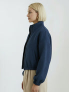 Cropped textured baseball jacket with full zipper and elastic cuffs, styled with high-waisted pants.