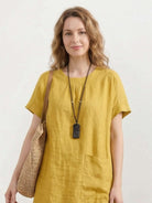 Woman wearing a relaxed 100% linen pocket midi dress with short sleeves and side slits
