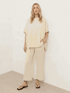 Woman wearing a chocolate brown cotton-blend capelet top with batwing sleeves and wide-leg pants lounge set