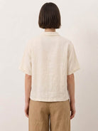 Woman wearing 100% linen top with relaxed fit and asymmetric button detail