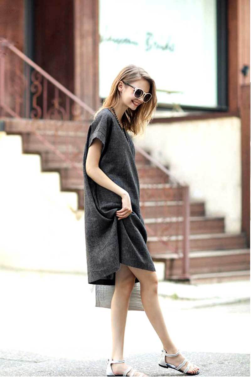 Woman wearing dark gray short sleeve shift dress with side pockets and sunglasses walking outdoors