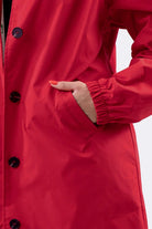 Close-up of a red water resistant oversized windbreaker with elastic cuff and front pocket detail