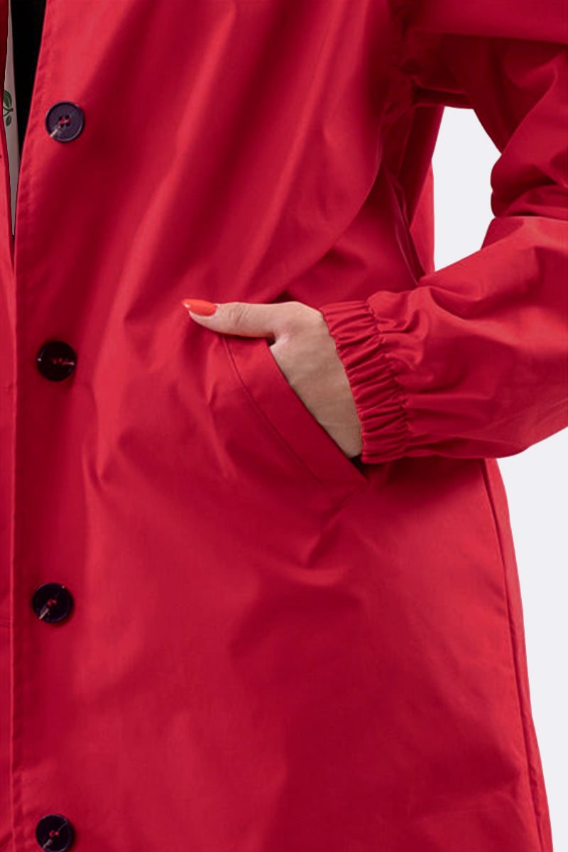 Close-up of a red water resistant oversized windbreaker with elastic cuff and front pocket detail