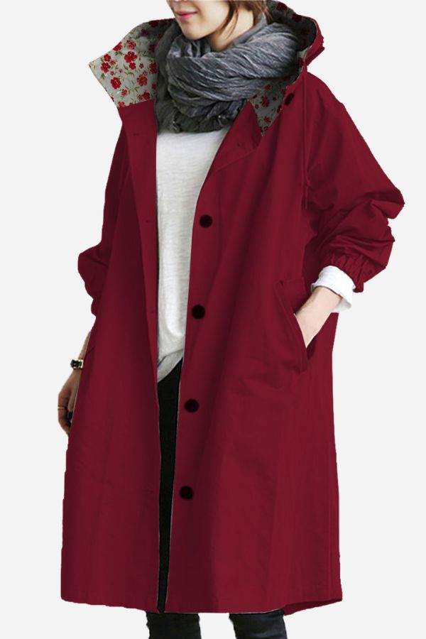 Water-resistant oversized windbreaker rain jacket in burgundy with floral inner lining, hooded and buttoned front, worn over casual outfit