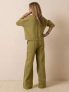 Woman wearing olive green short-sleeved pullover and wide trouser matching set viewed from the back.
