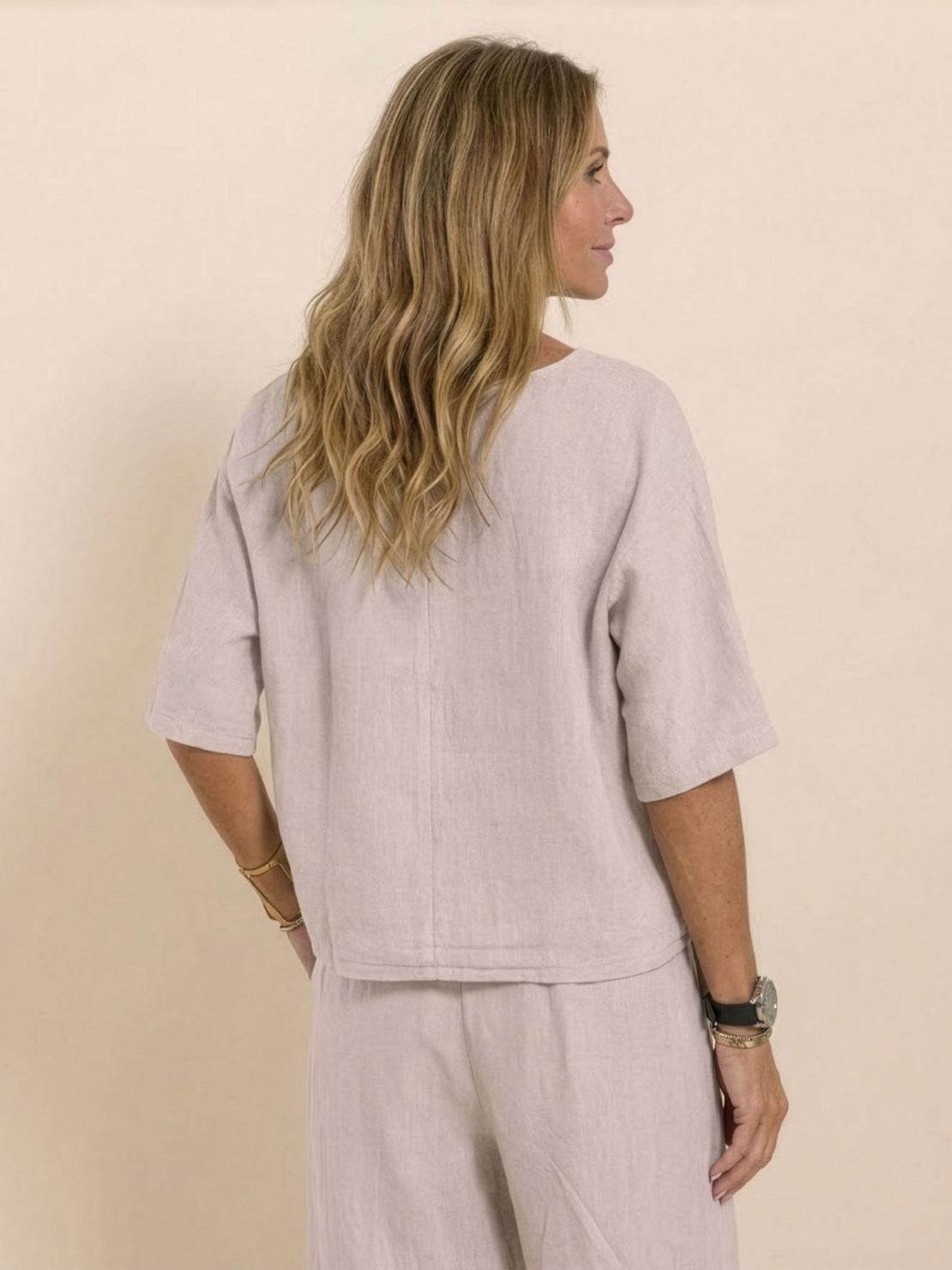 Woman wearing light beige short-sleeved pullover and wide trouser matching set from the back