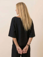 Back view of woman wearing black short-sleeved pullover and wide trouser matching set